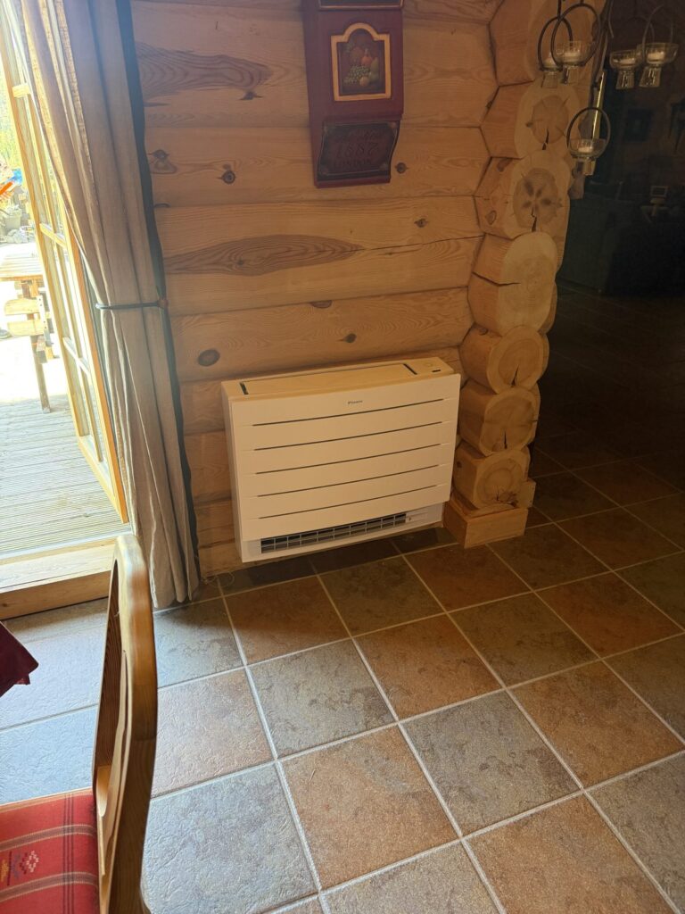 Daikin gulvmodell montert mot tømmervegg i hytte i Åseral