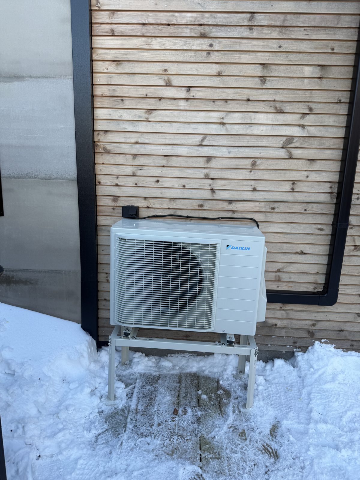 Daikin utedel på stativ mot trevegg i snø i Kristiansand
